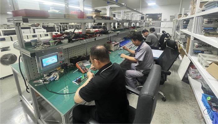Geliss freeze dryer manufacturing team - veteran engineers testing circuit boards with a multimeter and assembling lyophilizer units in the factory workshop